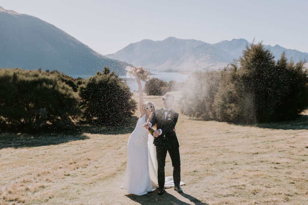 bride and groom doing a champagne spray with sunglasses on