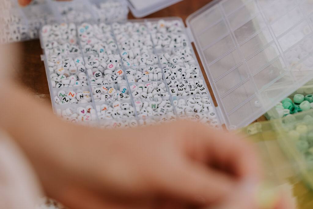 Detailed view of alphabet beads in trays for making kandi bracelets at the wedding.