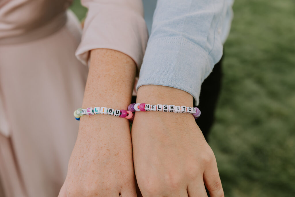 Two guests showing off their handmade kandi bracelets with personalised messages.