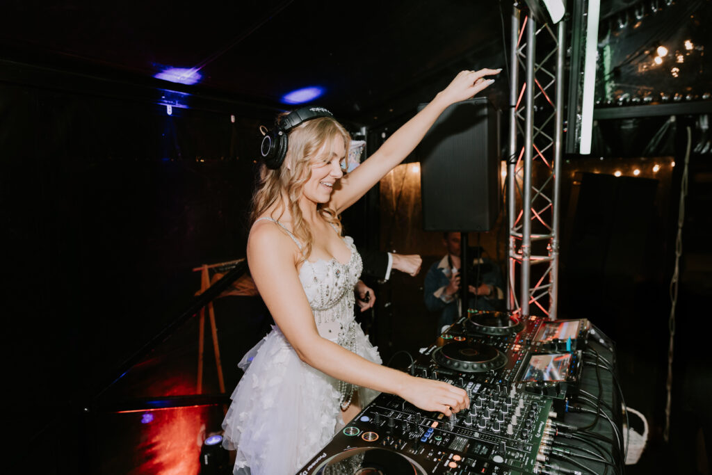 Bride DJing behind the decks in her party outfit during the festival-inspired wedding afterparty.