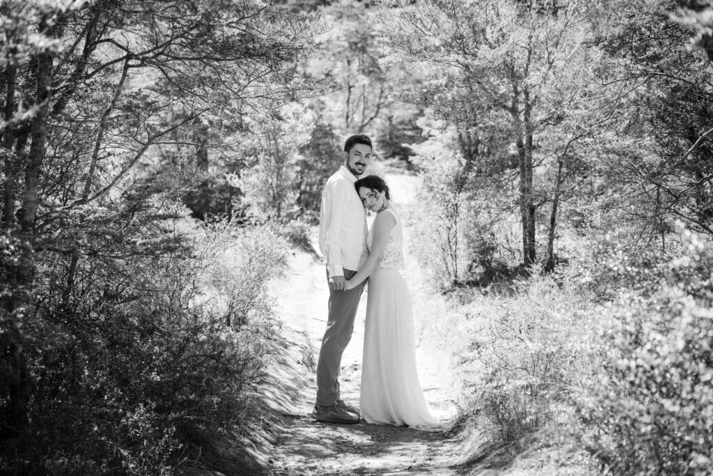 Couple embracing on a sunlit forest path during their Queenstown hiking elopement.