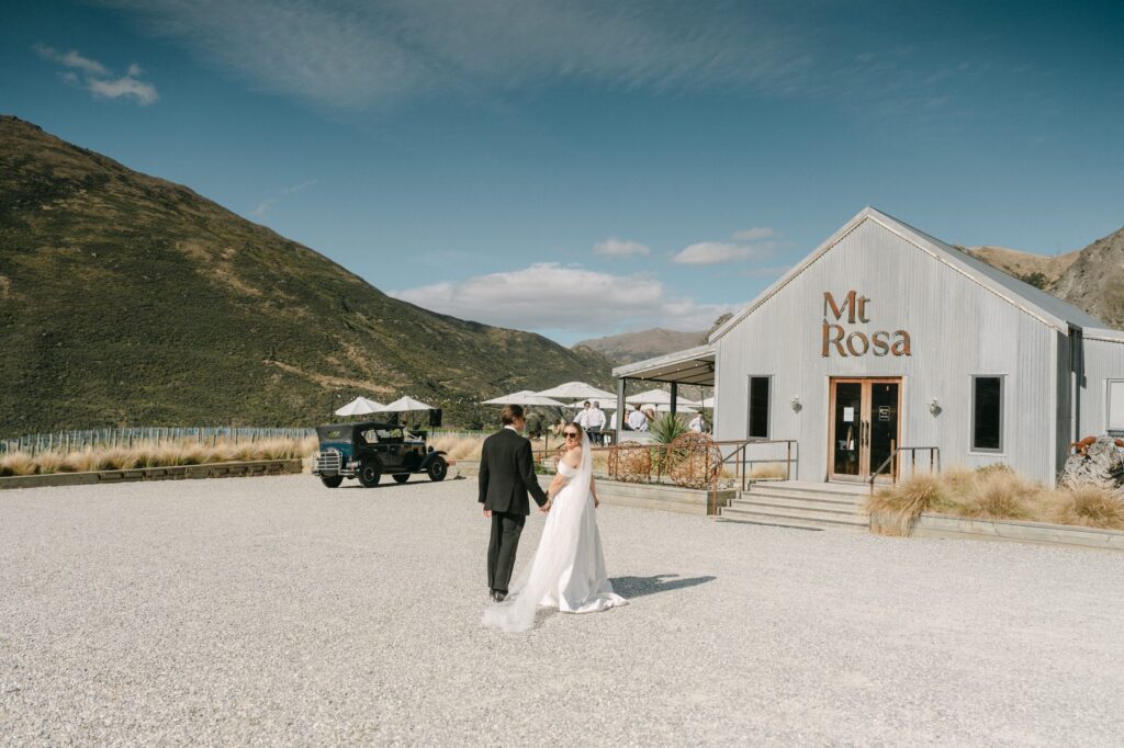 Bride and groom walking hand in hand outside the Mt Rosa venue building