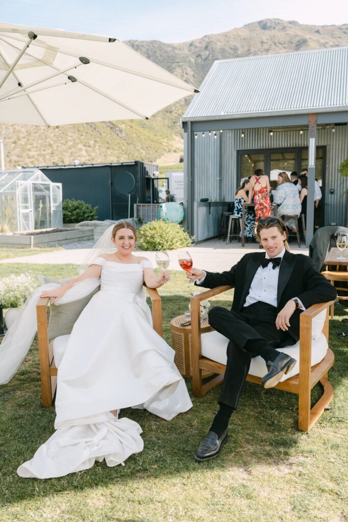 Bride and groom seated together holding drinks and laughing at their Mt Rosa reception